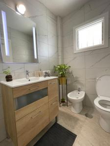 un bagno con lavandino, WC e specchio di Apartamento Garza Blanca a Bajamar Altre 30 foto