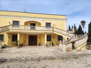 ein großes gelbes Haus mit einer großen Terrasse in der Unterkunft Villa Celea in Novoli