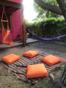 three orange pillows on a blanket next to a red building at Hostel Ruta76 in Sierra de la Ventana