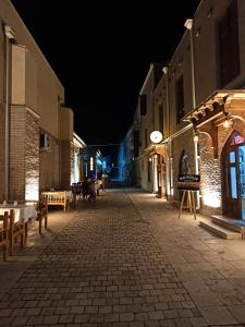 an empty street at night with a clock on a building at Miniature Boutique Hotel in Bukhara