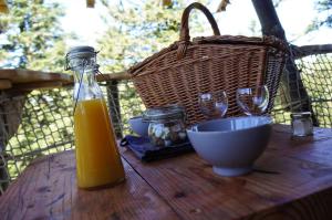 una botella de zumo de naranja en una mesa de madera con vasos y una cesta en Cabanes des Volcans, en La Tour-dʼAuvergne