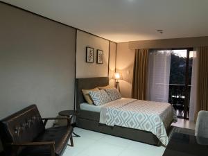 a bedroom with a bed and a chair and a window at Crosswinds Nature View Suite in Tagaytay