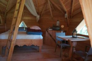 1 dormitorio en una cabaña de madera con 1 cama y 1 mesa en Cabanes des Volcans, en La Tour-dʼAuvergne