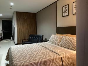a bedroom with a bed and a black chair at Crosswinds Nature View Suite in Tagaytay