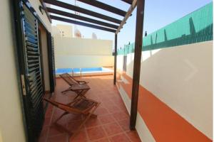a balcony with two chairs on top of a building at Villa con piscina, vistas, dunas, mar, 6 personas in Corralejo