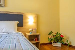 La Pineta - Le Casette di Osvaldo في ليكو: غرفة نوم مع سرير وزرع الفخار