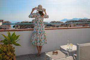 uma mulher de vestido e chapéu em pé na varanda em BW Premier Collection Mondial em Cannes
