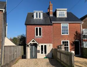 a brick house with a fence in front of it at Tile Cottage in Lymington