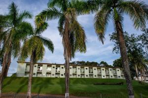 a building with palm trees in front of it at Hotel Fazenda Vale da Cachoeira in Serra Negra