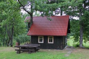 a small cabin with a red roof and picnic tables at Zirgu sēta "Klajumi" - Horse ranch "Klajumi" in Kaplava
