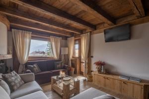 a living room with a couch and a tv on a wall at Cortina Lodge Stunning View R&R in Cortina dʼAmpezzo