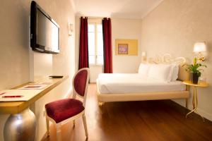 ローマにあるレジデンツァ フラッティナのベッド、デスク、テレビが備わるホテルルームです。