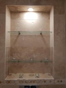 a shower with three glass shelves on the wall at Appartement en bord de mer in Cannes