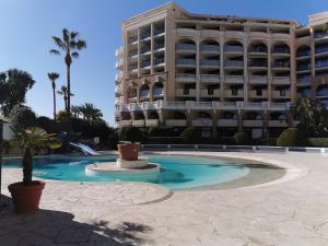 a swimming pool in front of a large building at Appartement en bord de mer in Cannes