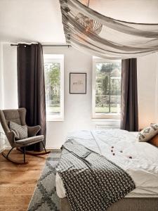 a bedroom with a bed and a chair and windows at Holiday Home Amélie in Bollendorf
