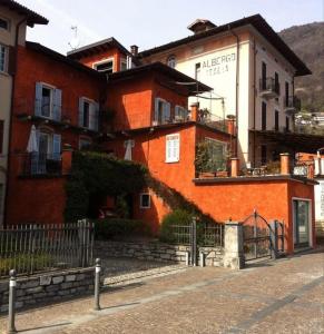 een oranje gebouw met een hek ervoor bij My Holidays - La Terrazza sul Lago in Gravedona