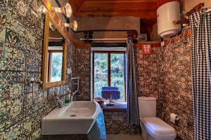 baño con lavabo y aseo y ventana en Barei Jungle Lodge en Chamba