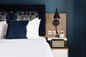 爱丁堡Heeton Concept Aparthotel Edinburgh Queen Street的一间拥有蓝色墙壁的卧室和一张带黑色床头板的床