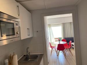 a kitchen with red chairs and a table and a window at Apartamento 29th floor & sea view in Alicante