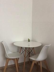 een witte tafel met twee stoelen en een tafel met een vaas erop bij Center Studio Apartment Podgorica in Podgorica