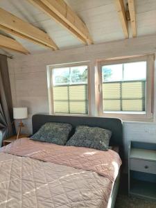 - un lit dans une petite chambre avec 2 fenêtres dans l'établissement Vila Preiloja - Žvejo namelis, à Neringa
