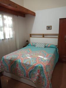 um quarto com uma cama com um cobertor colorido em Casa en Playas de Oro em San Antonio de Arredondo