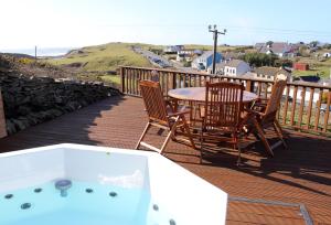 una terraza con mesa, sillas y bañera de hidromasaje. en Luxury Lodges in Doolin Village with Hot Tubs, en Doolin