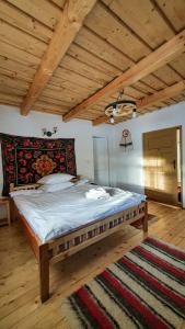 a large bed in a room with a wooden ceiling at Casuța din Grădină in Breb