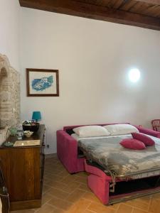 - une chambre avec un lit rose et un canapé dans l'établissement La Minicasa al Lago del Turano, à Castel di Tora
