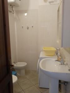 a white bathroom with a sink and a toilet at Terrazza sul mare climatizzata in Villaputzu