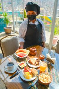 un uomo con una maschera per il viso seduto a un tavolo con prodotti per la colazione di Hotel Las Brisas Centro a La Paz