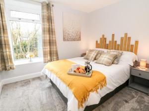 a bedroom with a bed with a tray of fruit on it at Bluebell Cottage in Birch Vale