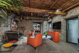 un salon avec des meubles orange et un mur en pierre dans l'établissement il Friscello, à Loro Ciuffenna