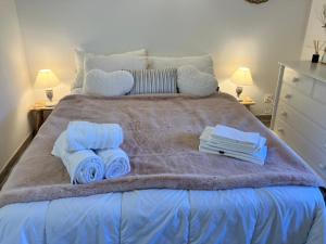 a bed with towels and books on top of it at Maison de montagne Alpes du sud/station Les Orres in Les Orres