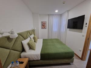a bedroom with a green bed and a couch at Soldouro Train Suites in Aveiro