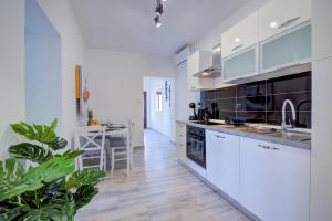a kitchen with white cabinets and a table in it at Apartments Maria in Senj