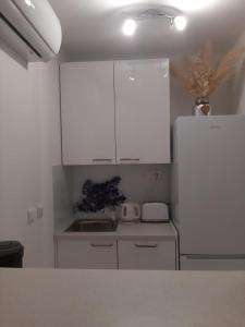 a kitchen with white cabinets and a white refrigerator at Apartman Sky in Pula