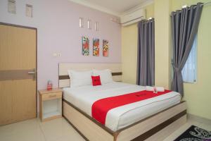 - une chambre avec un lit et une couverture rouge dans l'établissement RedDoorz Syariah Near Lapangan Dwiwarna Barabai, à Barabai