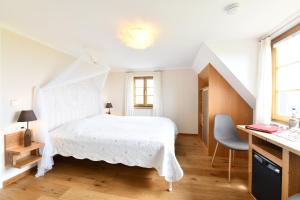 a bedroom with a white bed and a desk at Hotel Montfort-Schlössle in Lindau