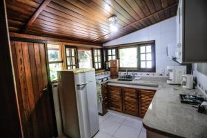 a kitchen with wooden ceilings and a white refrigerator at Sitio Bom Tempo in Miguel Pereira