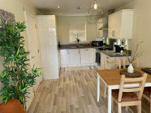a kitchen with white cabinets and a table with chairs at Stunning 3 bedroom home with free parking, free wifi and Netflix, Company workers welcome short term and long term in Castleford