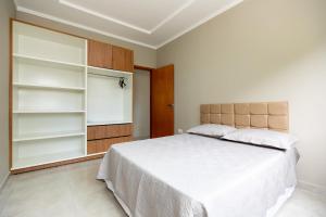 - une chambre avec un grand lit blanc et des étagères dans l'établissement Apartamento região central de foz do Iguaçu, à Foz do Iguaçu