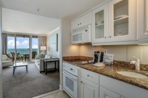 a kitchen with a sink and a living room at Marco Beach Ocean Resort 807 in Marco Island