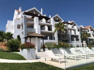 ein großes weißes Wohnhaus mit Liegestühlen davor in der Unterkunft Casa Dollita - Semi Penthouse - 90 square meters terrace -breathtaking seaview in Mijas