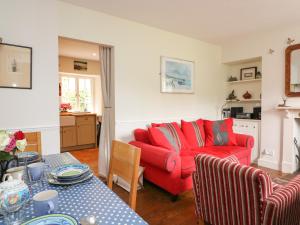 a living room with a red couch and a table at Coastguard Cottage in Dartmouth