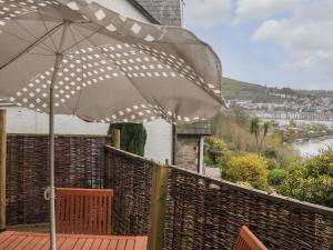 a patio with an umbrella and chairs on a deck at Coastguard Cottage in Dartmouth