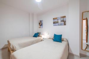 two beds in a room with white walls and blue pillows at Record Maritim II in Port d'Alcudia