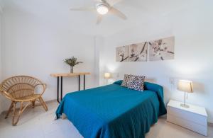 a bedroom with a blue bed and a chair at Record Maritim II in Port d'Alcudia
