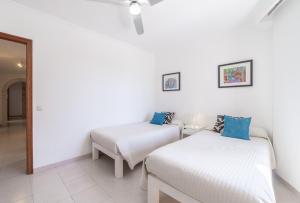 two beds in a room with white walls and blue pillows at Record Maritim II in Port d'Alcudia
