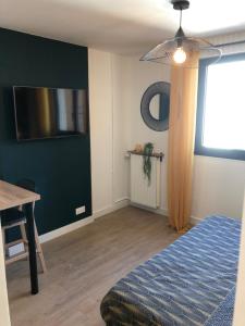 a bedroom with a bed and a table and a television at Concarneau centre-ville proche plage in Concarneau